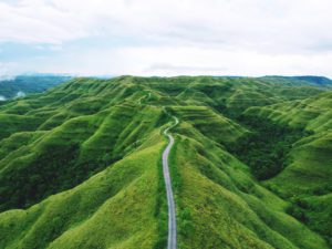 A long winding road between green hills